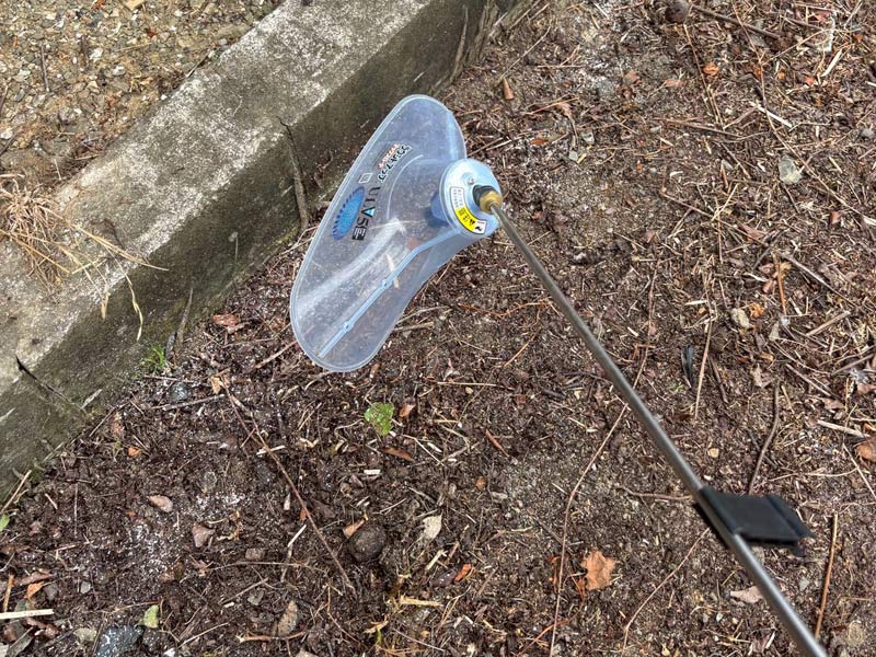 空き家管理で敷地内へ飛散防止カバー付きノズルを使用して除草剤を散布している様子