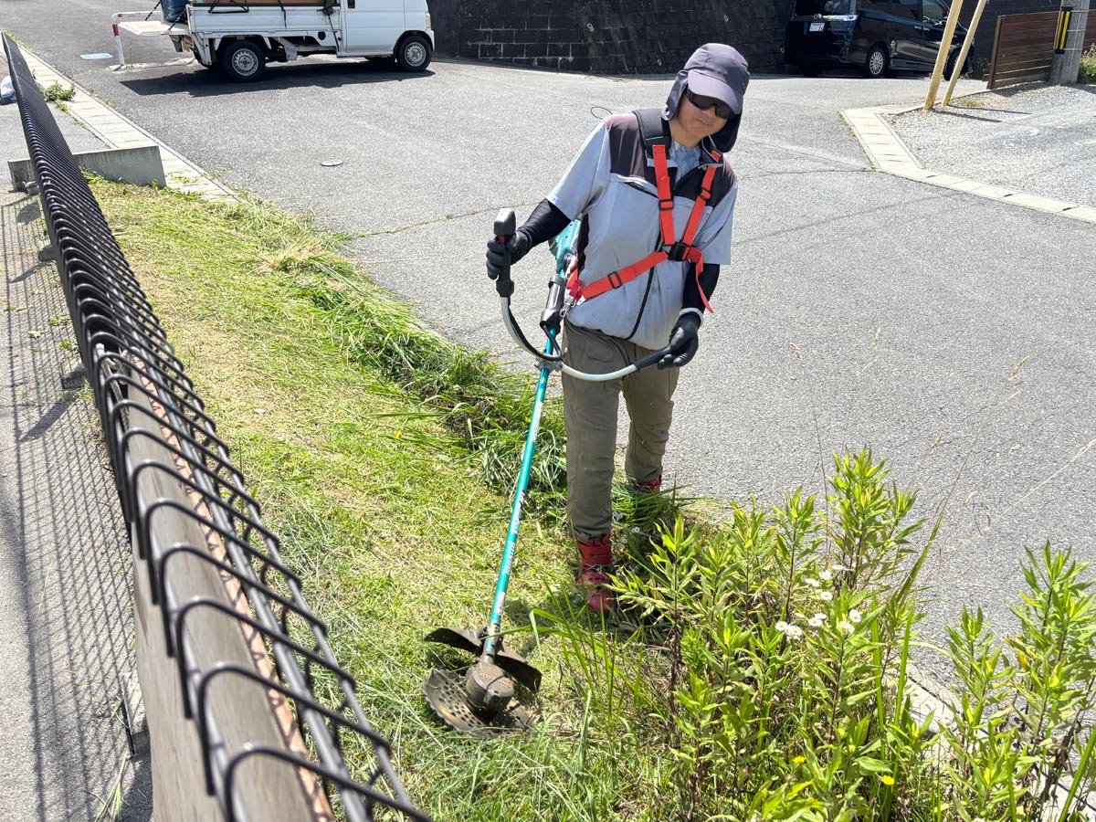 石巻市須江地区のアパート敷地周り、電動刈払機を使った斜面の草刈り作業中の様子