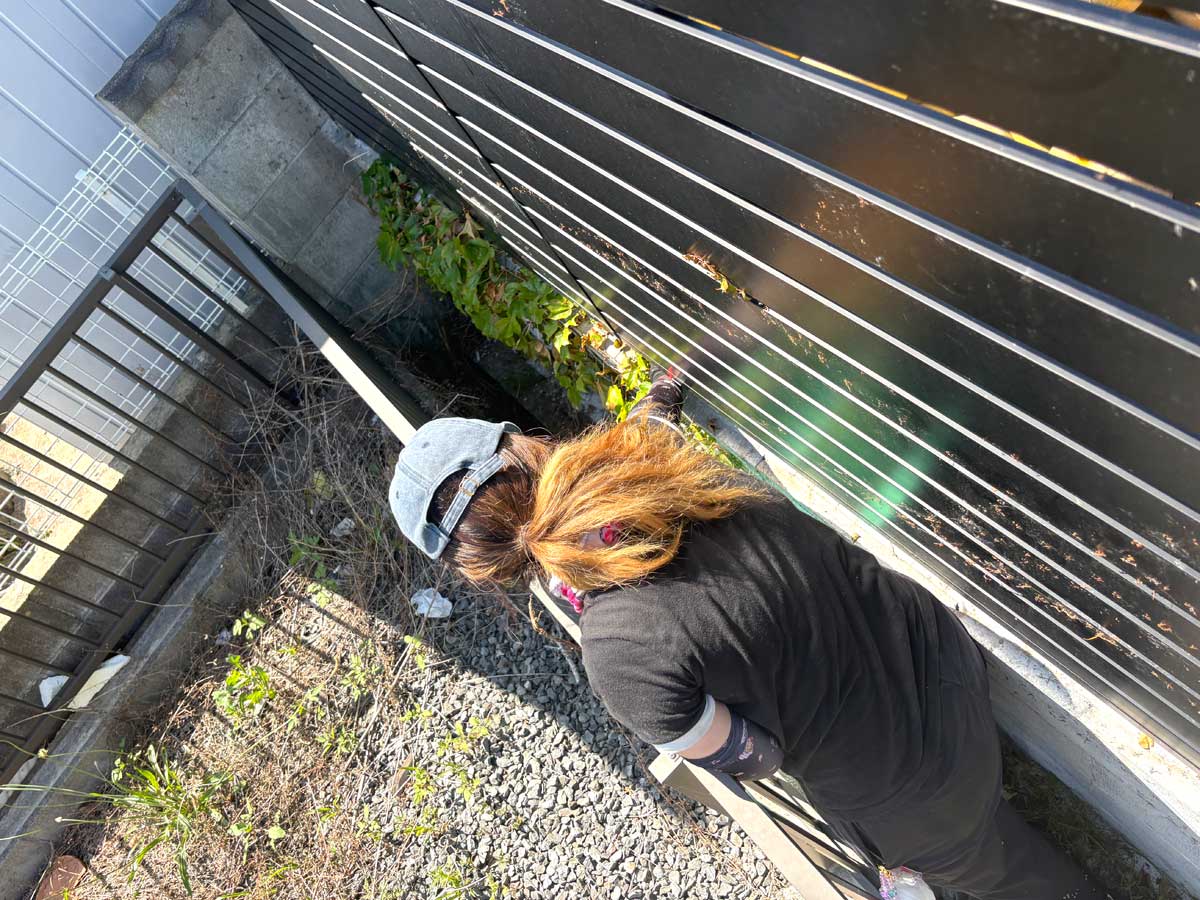 石巻市湊地区の漁具資材置き場でフェンスに絡んだツタを手作業で除去している様子