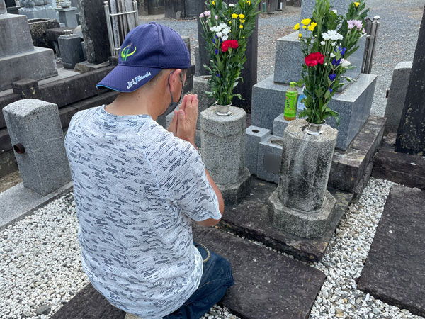 便利屋フォーカスのお墓掃除サービス（お墓参り代行でお花お線香をお供えして合掌中の様子。）
